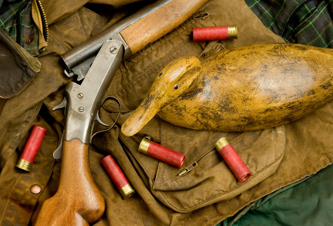 Hunting gear with shotgun and duck decoy.